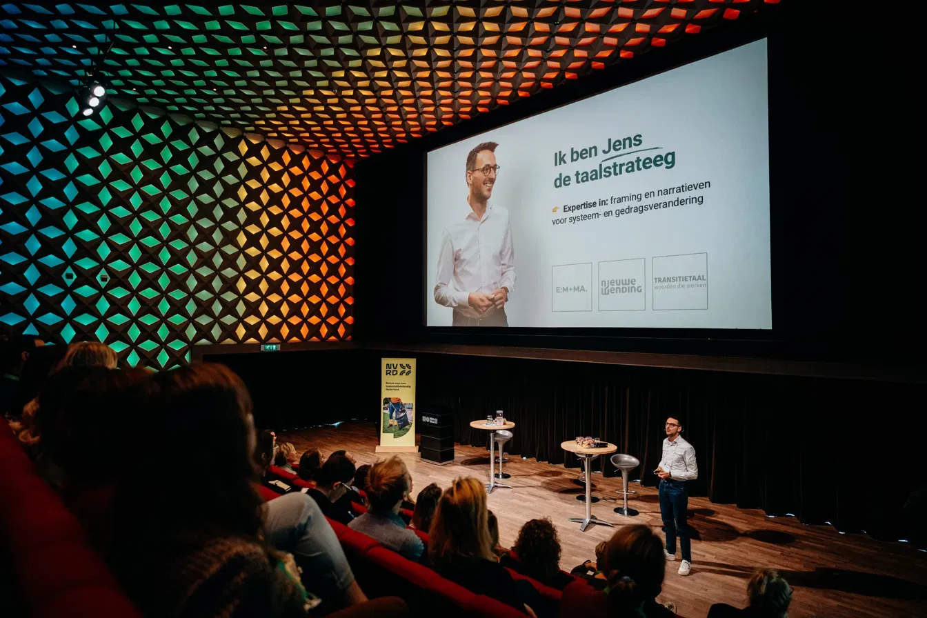 Keynote voor een volle zaal onder een kleurrijk plafond